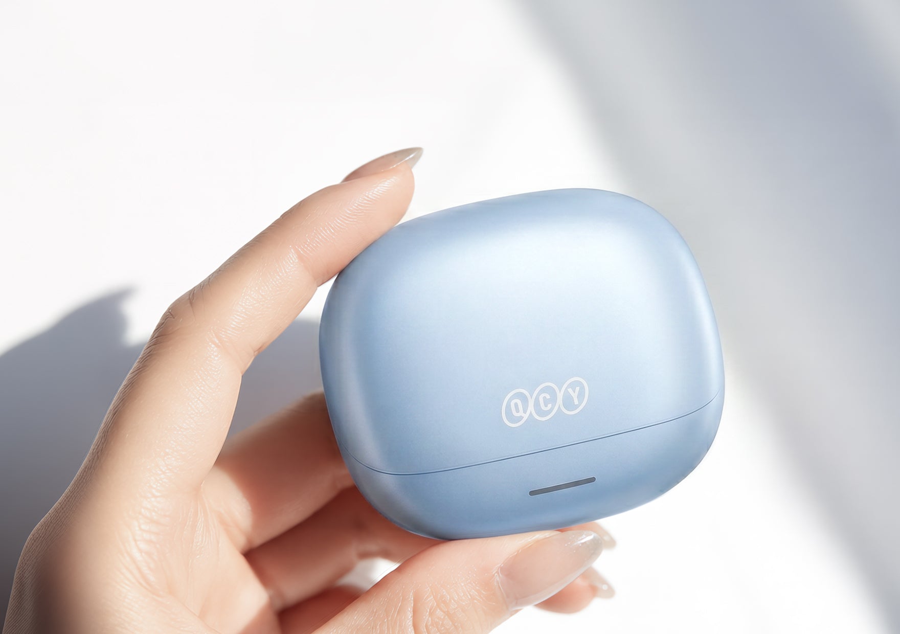 Écouteurs Bluetooth QCY bleu clair, maintenus dans leur boîtier de chargement.