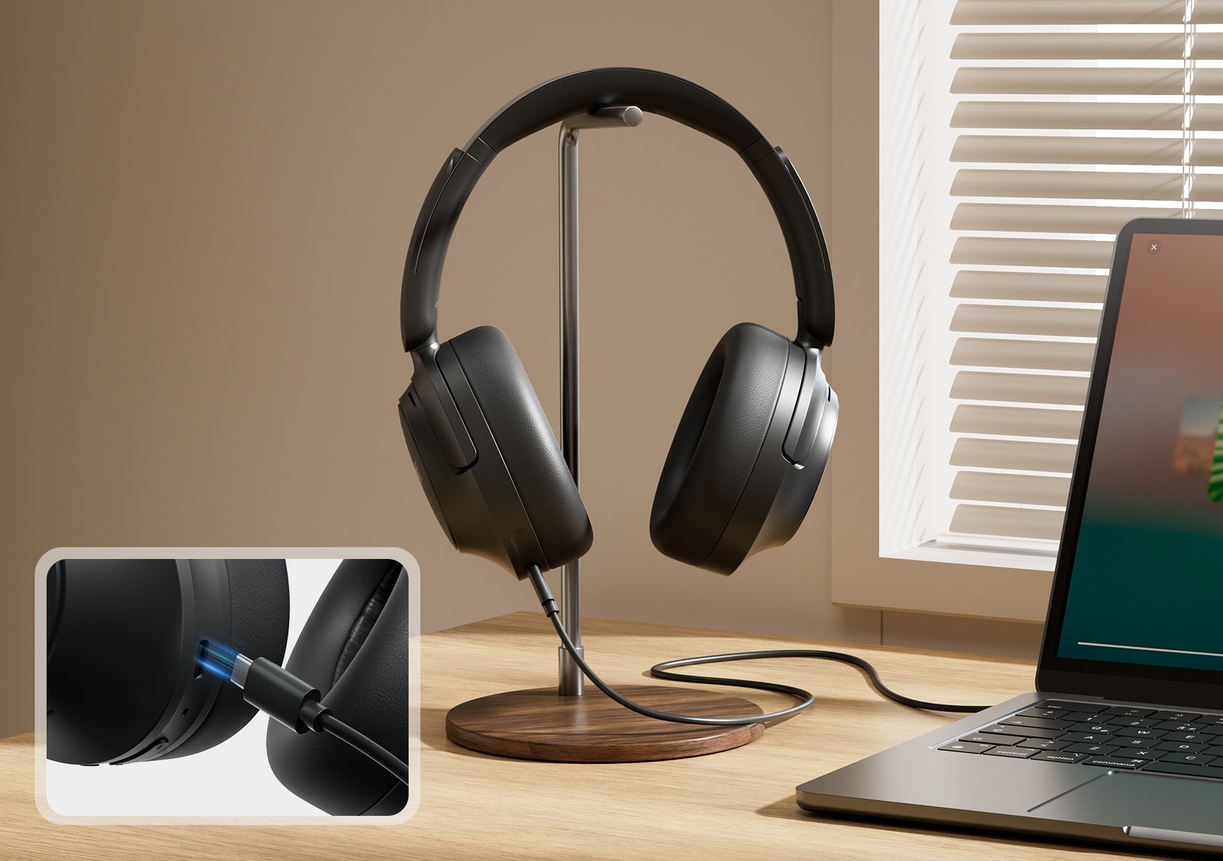 Casque noir circum-aural avec câble sur un support en bois à côté d’un ordinateur portable près de la fenêtre.