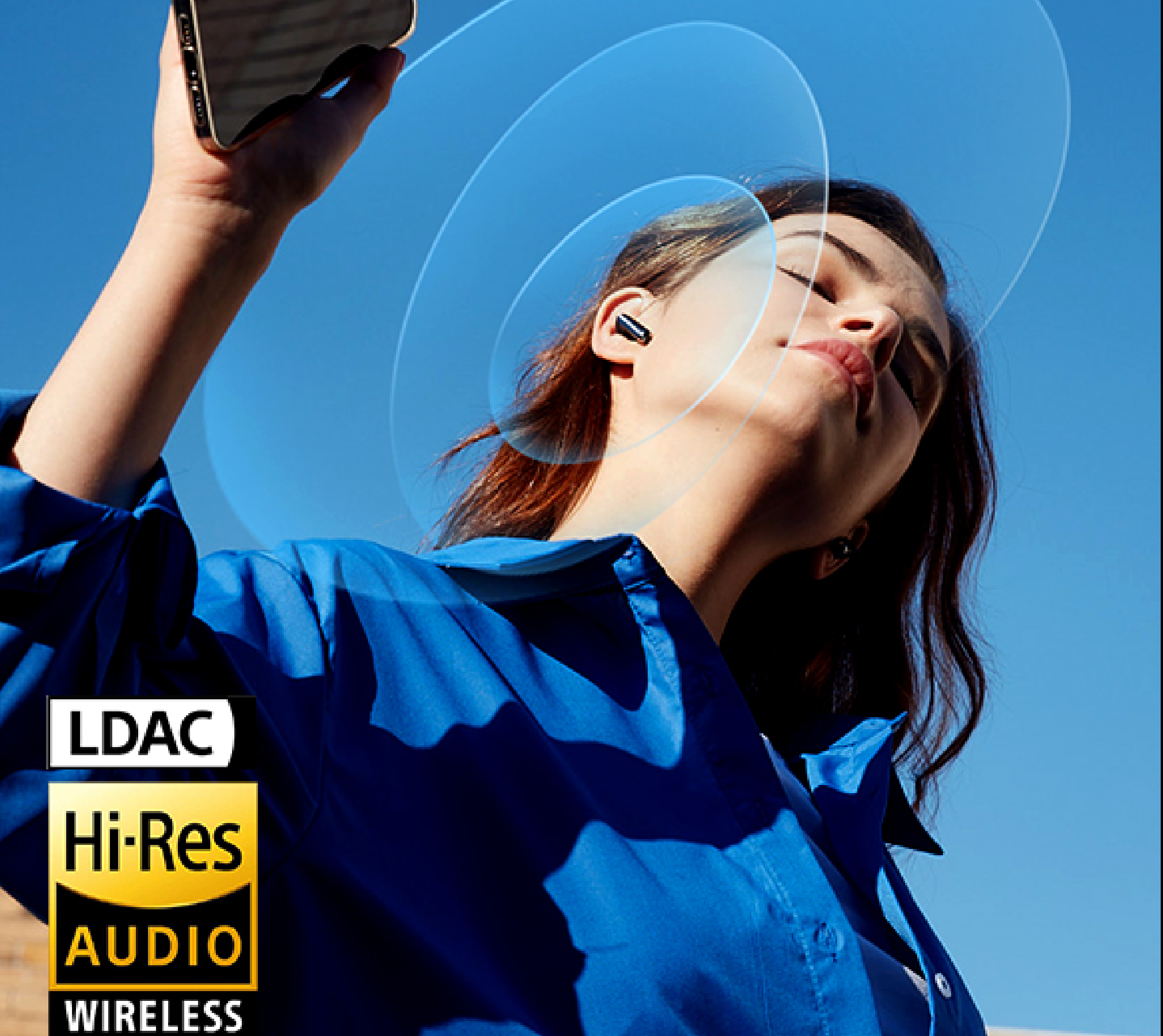 Femme avec des écouteurs Hi-Res Audio sans fil sous un ciel bleu, profitant de la musique via la technologie sans fil LDAC.