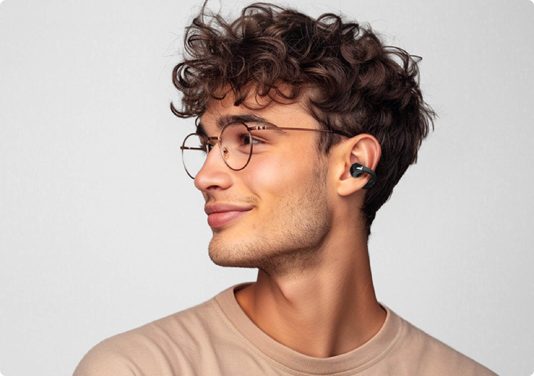 Jeune homme portant des lunettes et des écouteurs sans fil de profil.