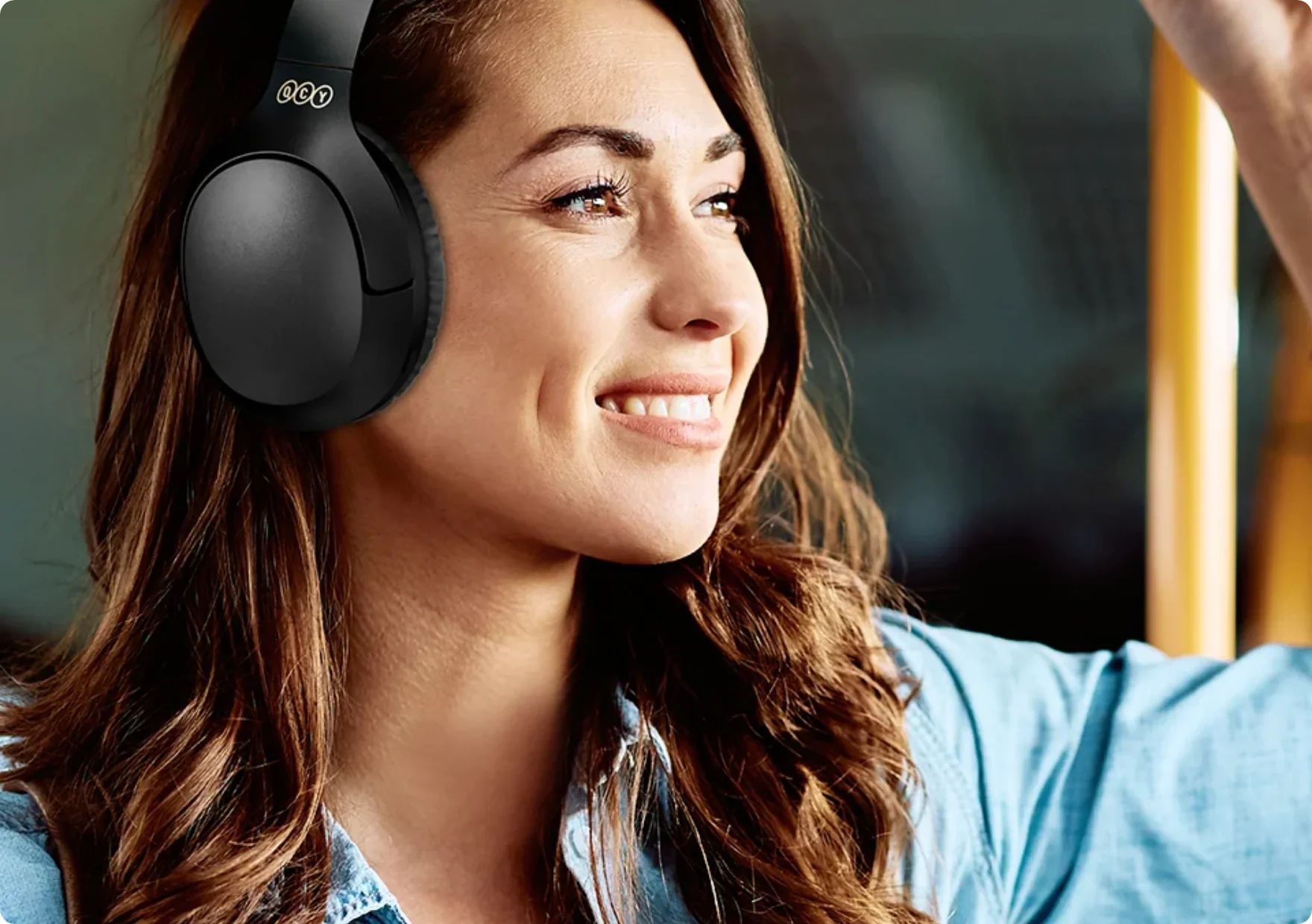 Femme souriante avec des écouteurs noirs circum-auriculaires dans le bus.