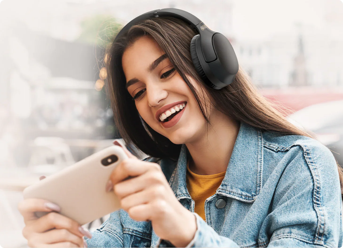 Femme souriante avec des écouteurs sans fil et un smartphone.