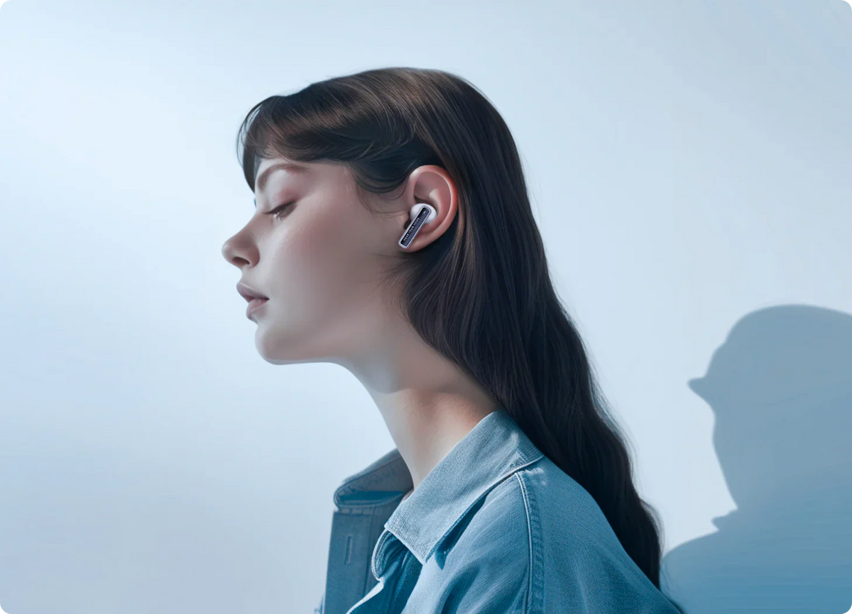 Femme avec des écouteurs Bluetooth blancs en veste en jean, vue de profil