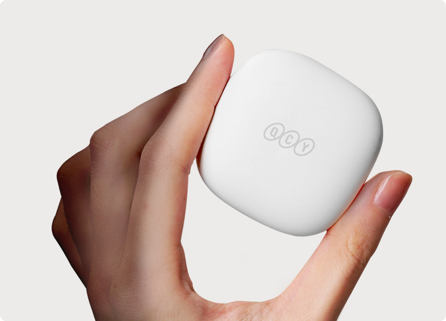 Boîtier d'écouteurs QCY blanc dans la main, design minimaliste avec logo, idéal pour les écouteurs sans fil.