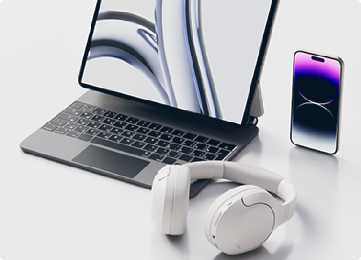 Ensemble moderne d’ordinateur portable avec casque blanc et smartphone sur une table claire.