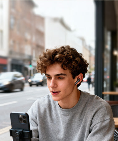 Jeune homme avec des écouteurs sans fil et un smartphone en ville