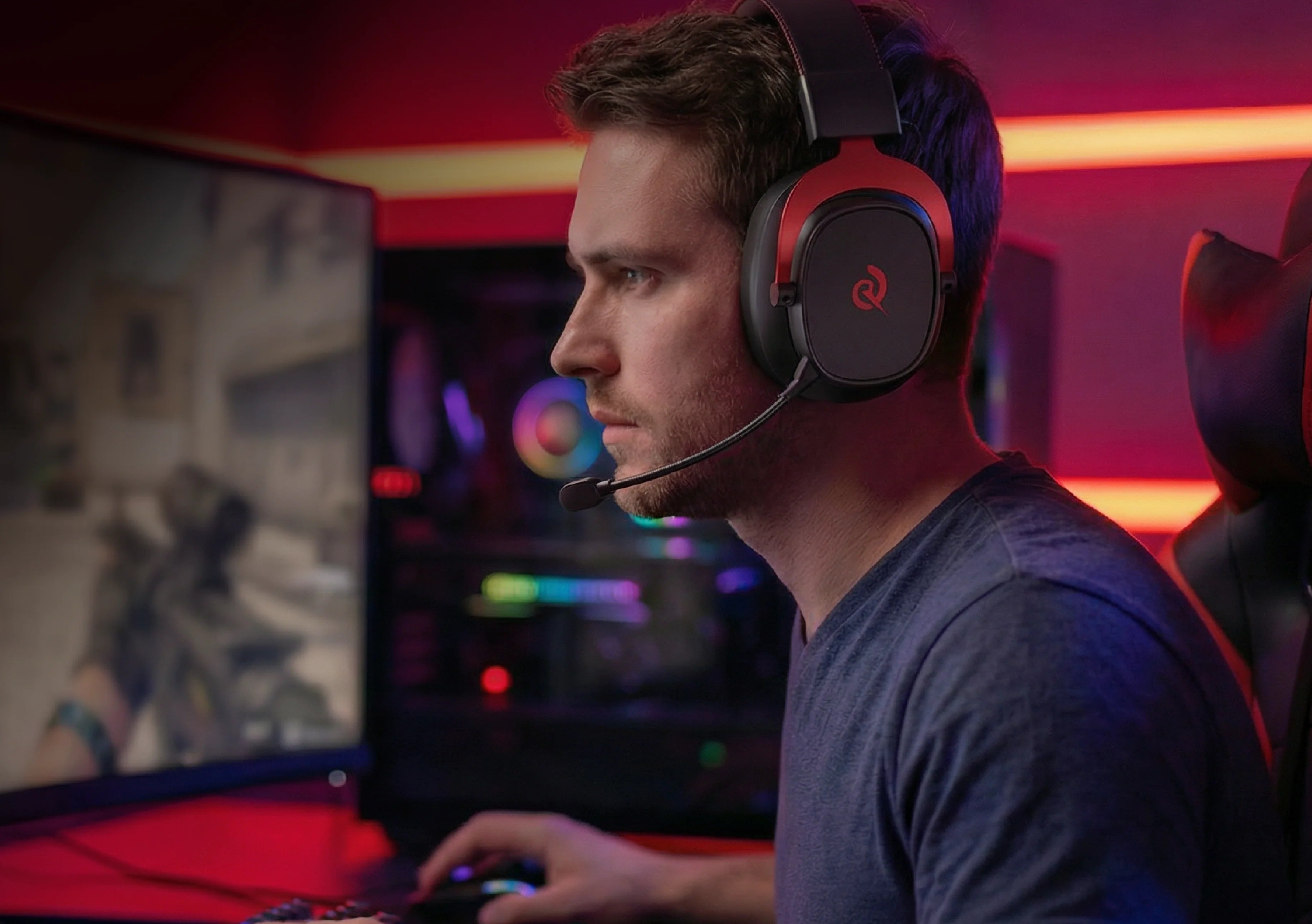 Homme avec casque de jeu et microphone devant un écran d’ordinateur, éclairage RGB lumineux en arrière-plan