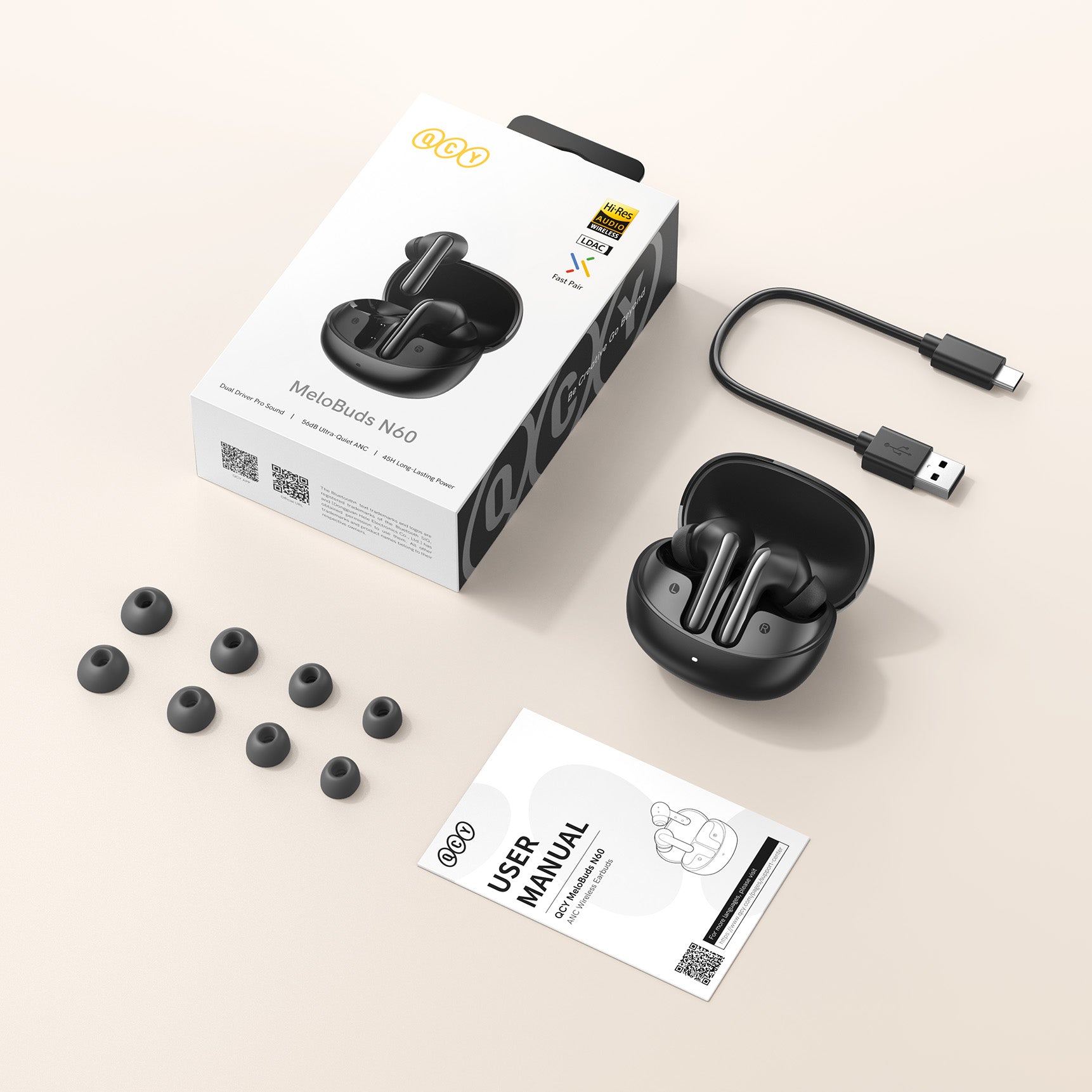 Écouteurs sans fil QCY MeloBuds N60 avec boîtier de chargement, câble USB, embouts de rechange et mode d'emploi sur fond clair